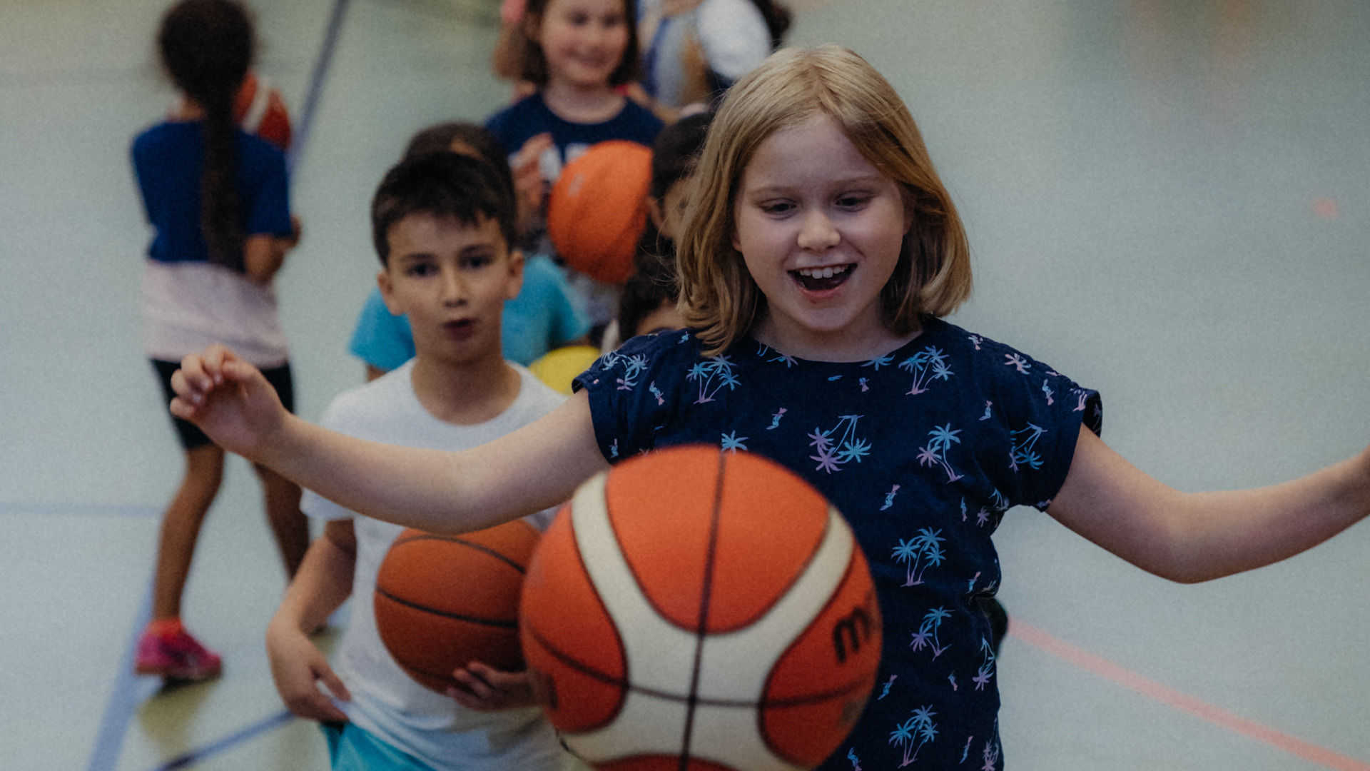 Ein Mädchen freut sich über einen erfolgreichen Wurf bei der Basketball Grundschulwoche 2022 in einer Berliner Schule.